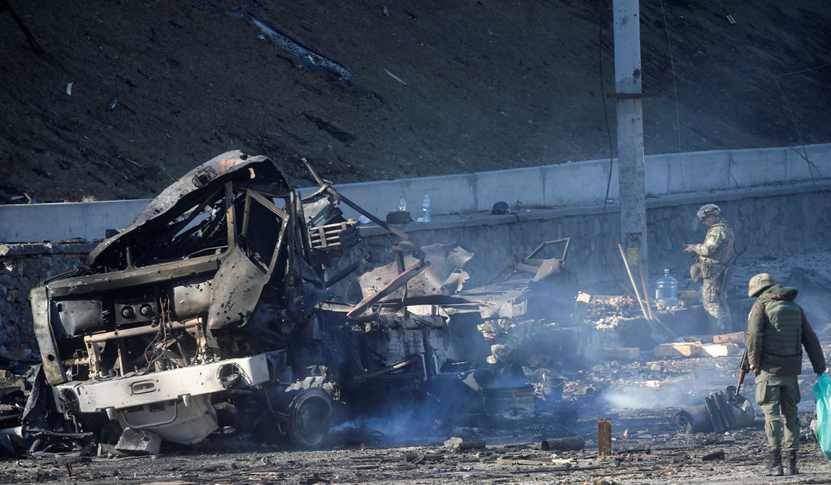 Ukrainian servicemen inspect a damaged vehicle